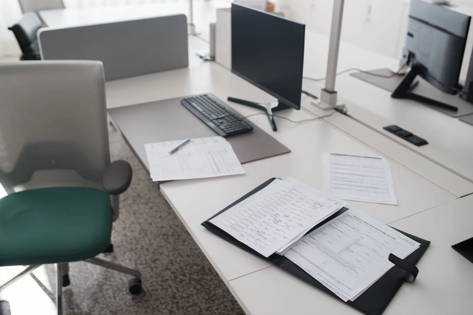 Checkliste Büroreinigung: täglich, wöchentlich, monatlich Aufgeräumter Büroarbeitsplatz mit Monitor, Tastatur und Ordnern auf dem Tisch
