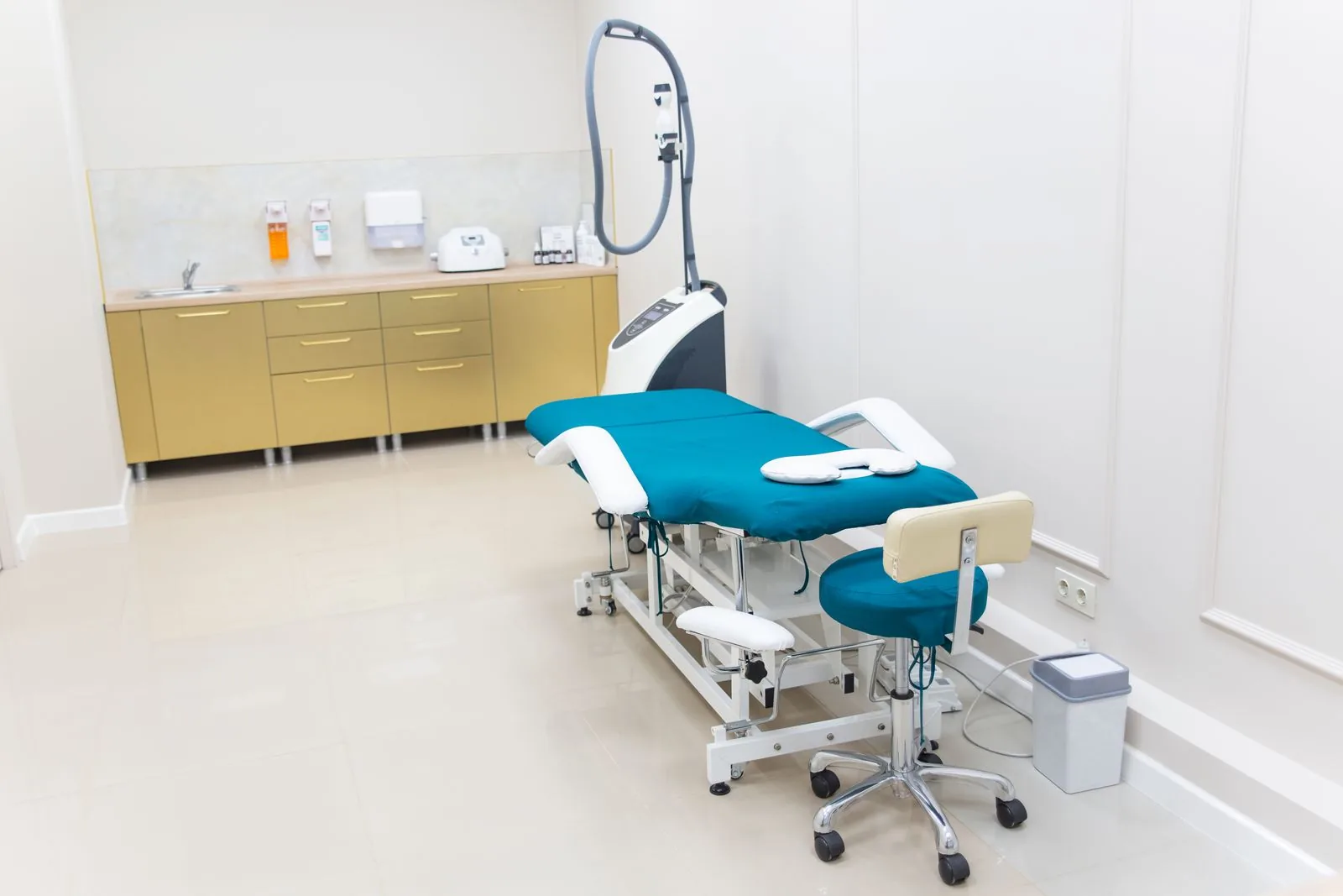 Was der Hygieneplan für die Reinigung vorgibt Heller Behandlungsraum mit Liege, Waschbecken und Wandspendern für Desinfektionsmittel und Papierhandtücher