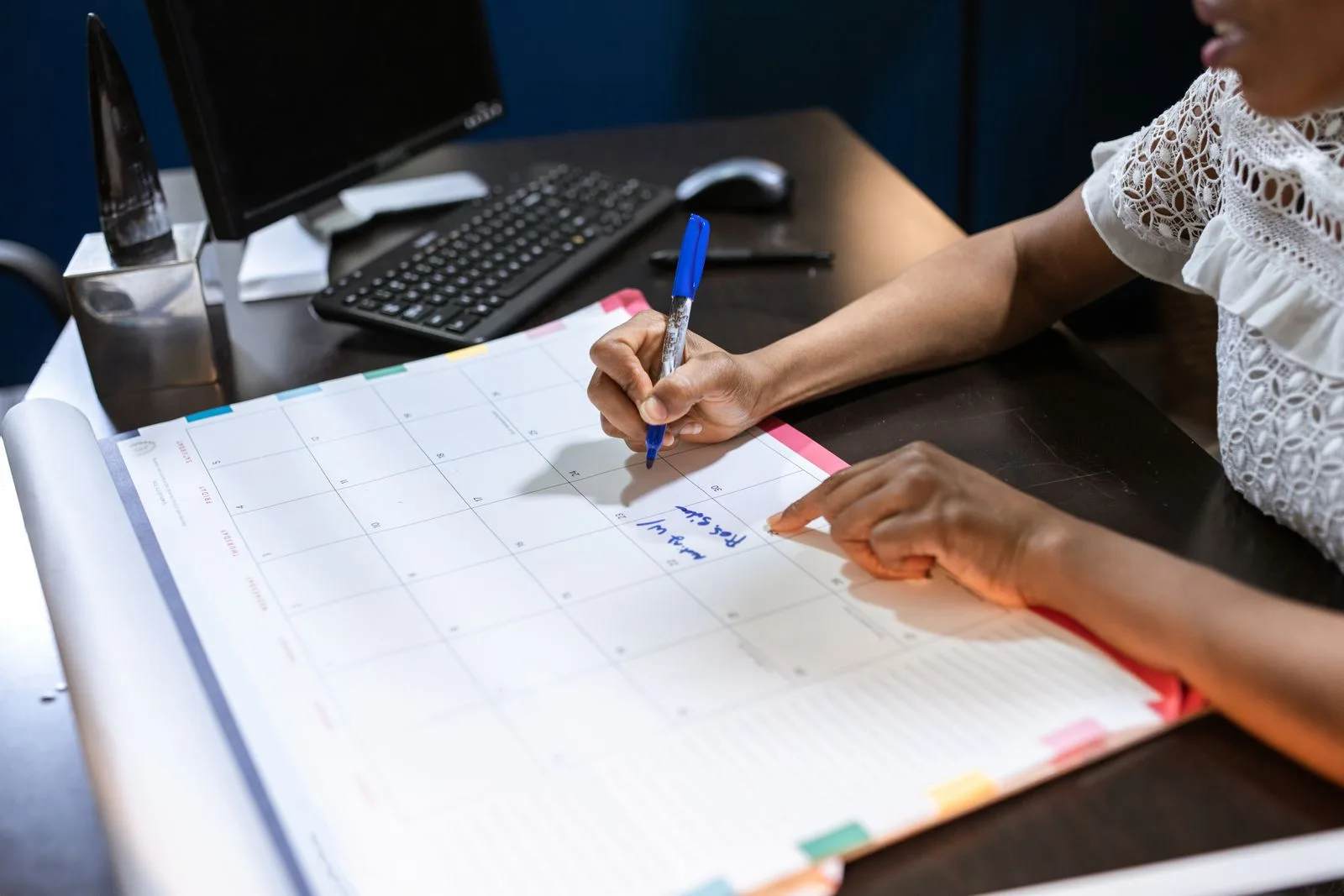 Jahresplanung Reinigung: was Hausverwaltungen jetzt klären sollten Hände tragen mit blauem Stift einen Termin in einen großen Monatskalender auf einem Schreibtisch ein