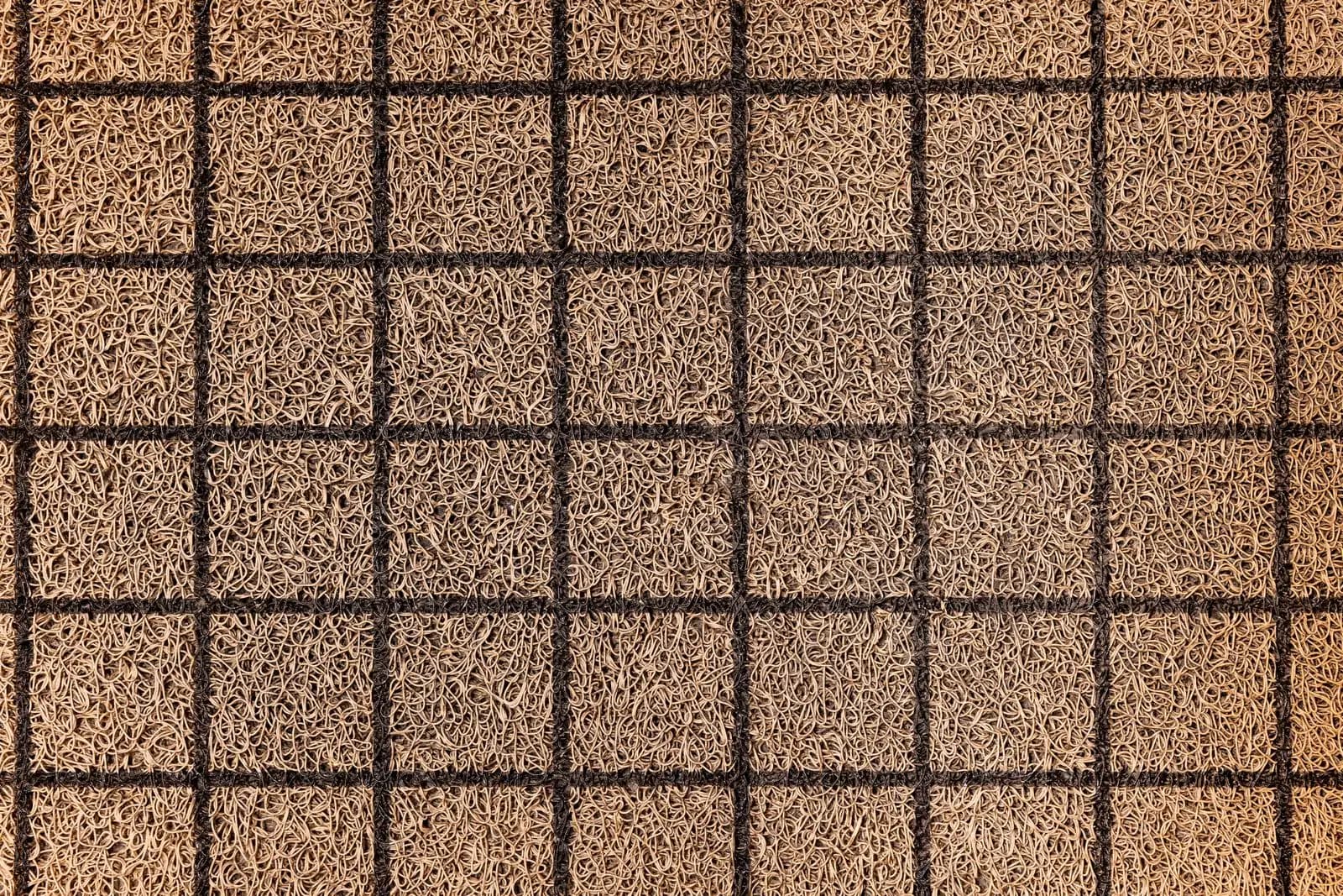 Schmutzfangzone im Eingang: der günstigste Reinigungstrick Draufsicht auf eine beige Schlingenmatte mit dunklem Rastermuster, wie sie in Eingangsbereichen als Schmutzfang liegt