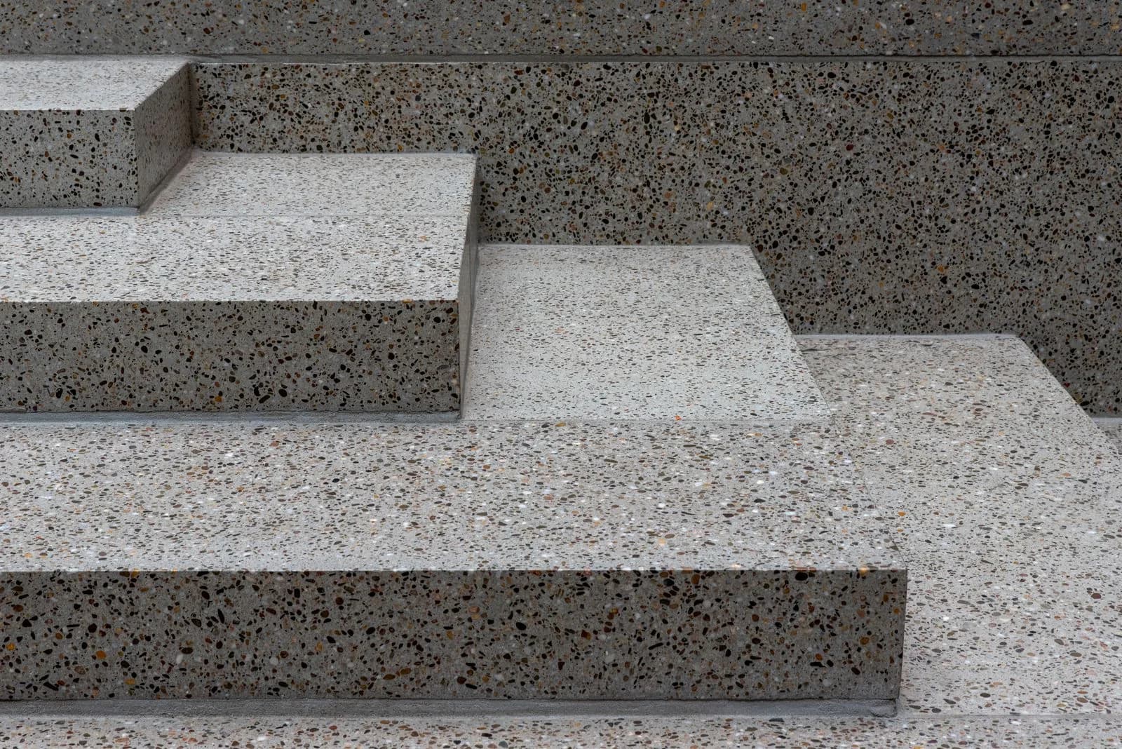Terrazzo, Marmor und Linoleum im Treppenhaus richtig pflegen Nahaufnahme von Treppenstufen aus geschliffenem Terrazzo mit grober Zuschlagskörnung in Grau und Braun
